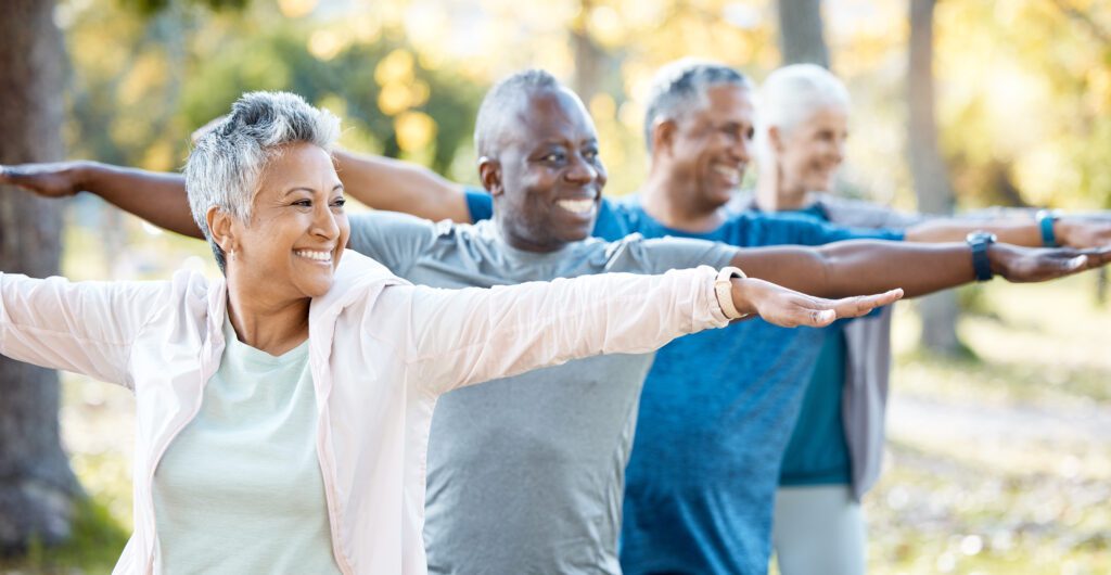 Group of senior individuals in a park stretching.