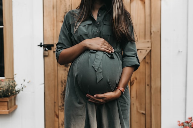 Pregnant women holding her belly in front of door
